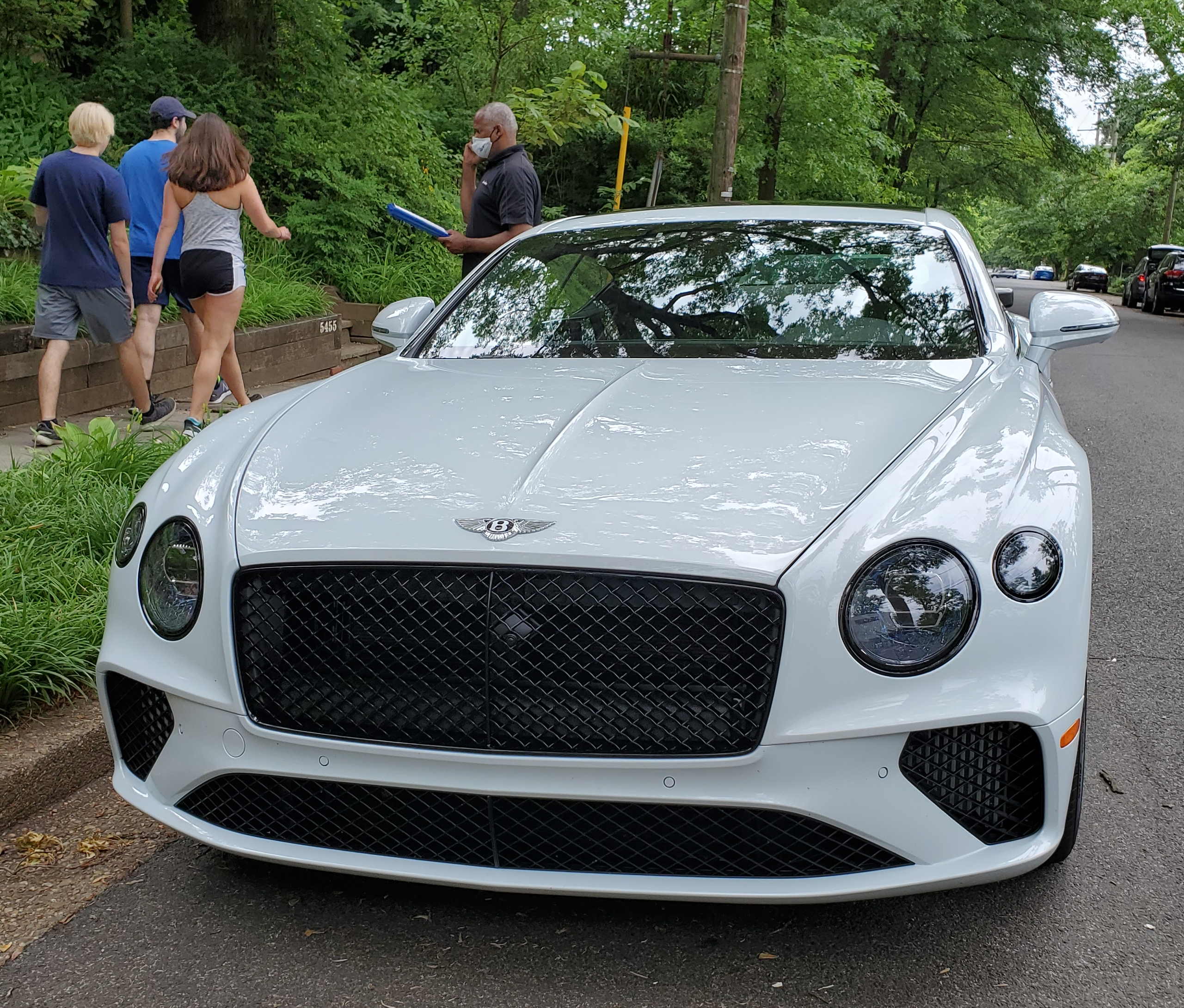 White Bentley Continental GT V8 with people beside it.