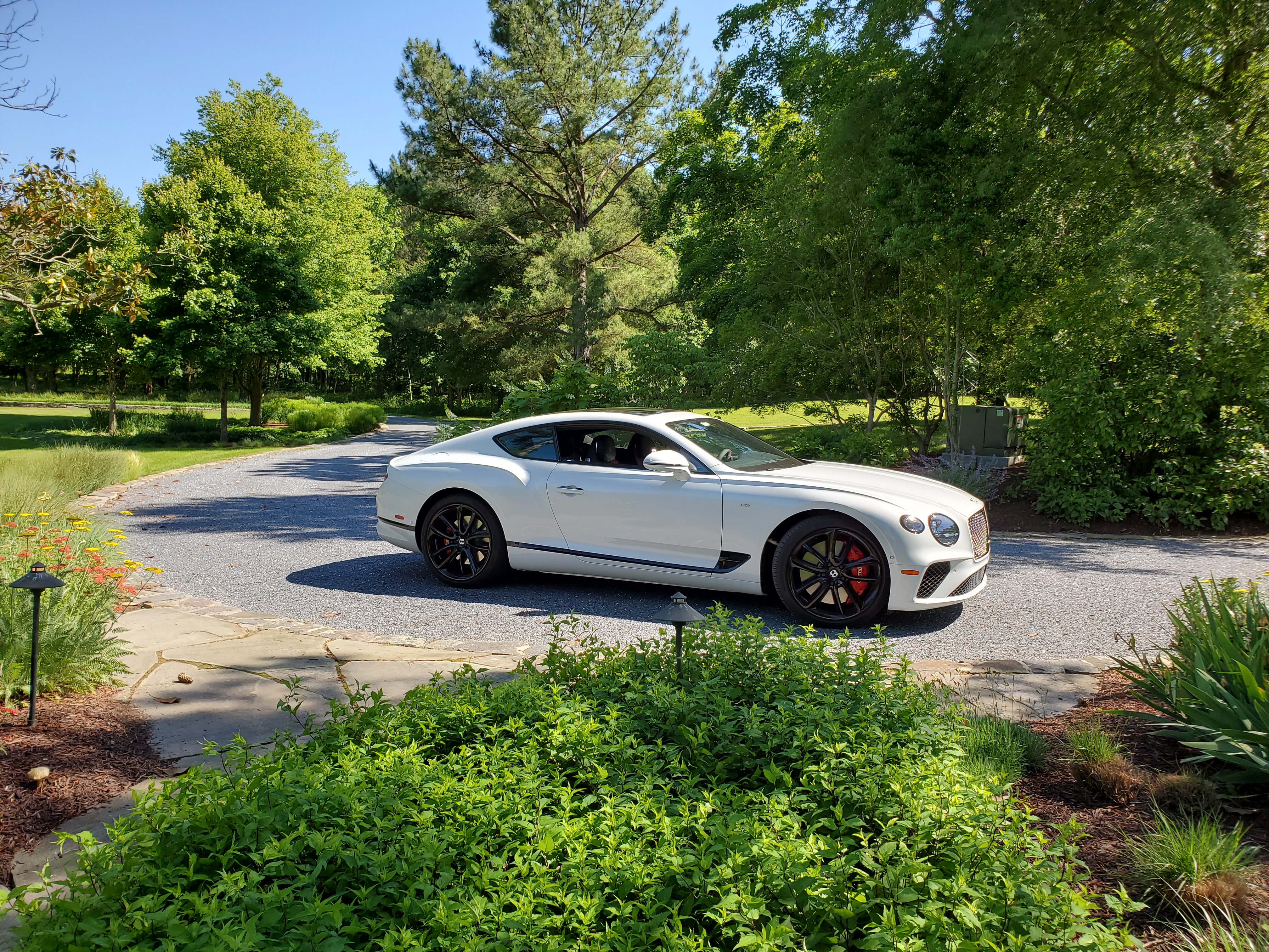 bentley continental gt v8 in ice on gravel driveway with greenery surrounding it